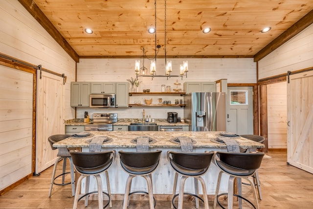 kitchen featuring wood ceiling, a barn door, wood walls, and appliances with stainless steel finishes