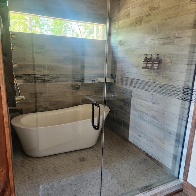 bathroom with tile walls, a soaking tub, tile patterned floors, and a stall shower