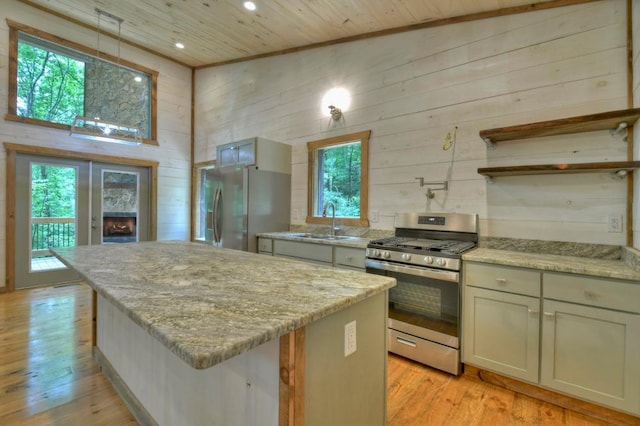 kitchen with stainless steel appliances, a center island, a sink, wood walls, and wood ceiling