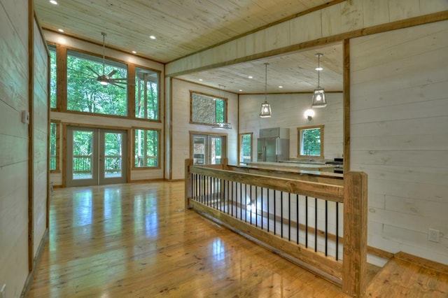 interior space featuring a ceiling fan, wood walls, wood ceiling, wood-type flooring, and a high ceiling