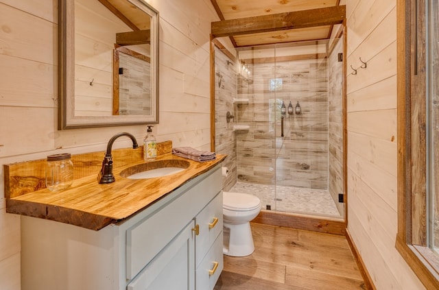 full bath featuring wood walls, wood finished floors, toilet, vanity, and a stall shower