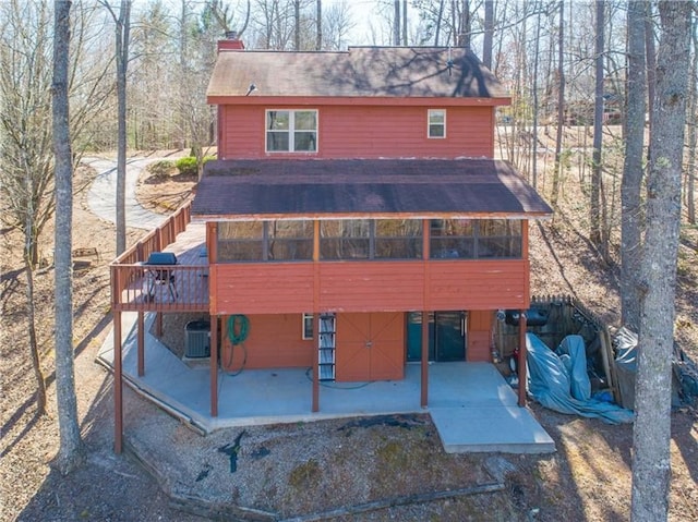 view of front of property with cooling unit, a wooden deck, a chimney, and a patio area