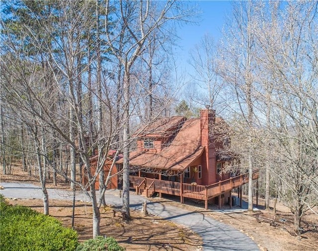 exterior space with aphalt driveway, a chimney, and a deck