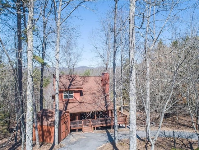 exterior space featuring driveway, a chimney, and a deck