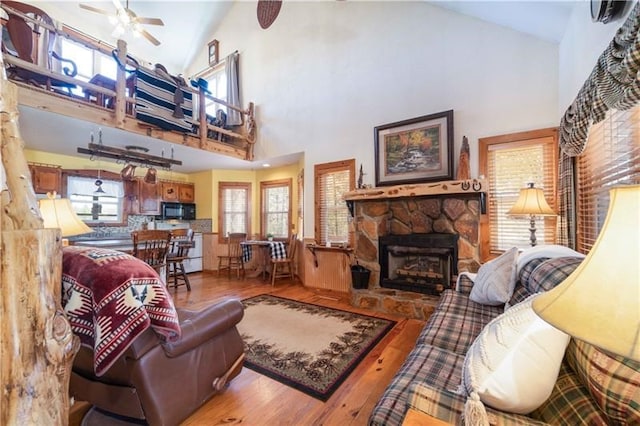 living room with a wealth of natural light, a ceiling fan, wood finished floors, and a fireplace