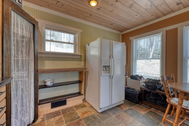 kitchen with wooden ceiling, visible vents, white fridge with ice dispenser, and stone tile flooring