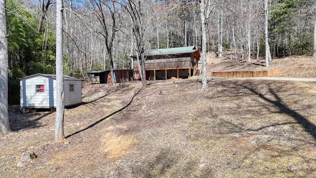 view of front of house featuring a view of trees, fence, an outdoor structure, and a shed