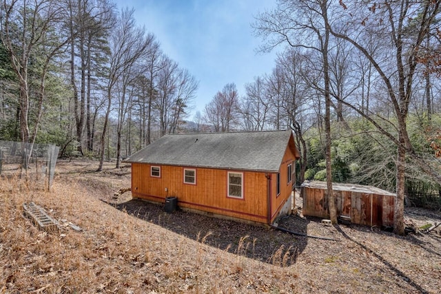 back of house featuring central air condition unit, roof with shingles, and a hot tub