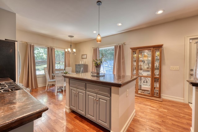 kitchen featuring a center island, hanging light fixtures, light hardwood / wood-style flooring, gray cabinets, and stainless steel refrigerator