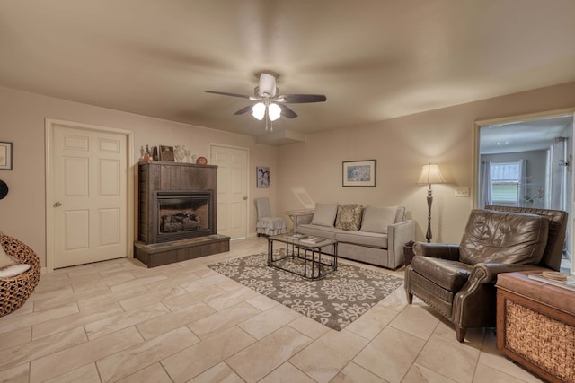 living room with ceiling fan and a tiled fireplace