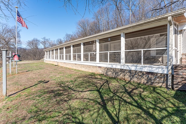 view of home's exterior with a sunroom and a lawn