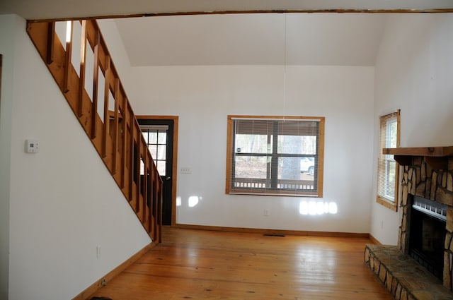 unfurnished living room featuring a stone fireplace and light hardwood / wood-style floors