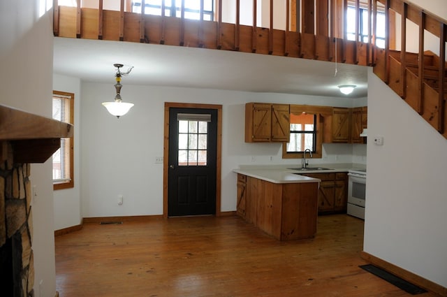 kitchen featuring hardwood / wood-style floors, sink, pendant lighting, and white stove