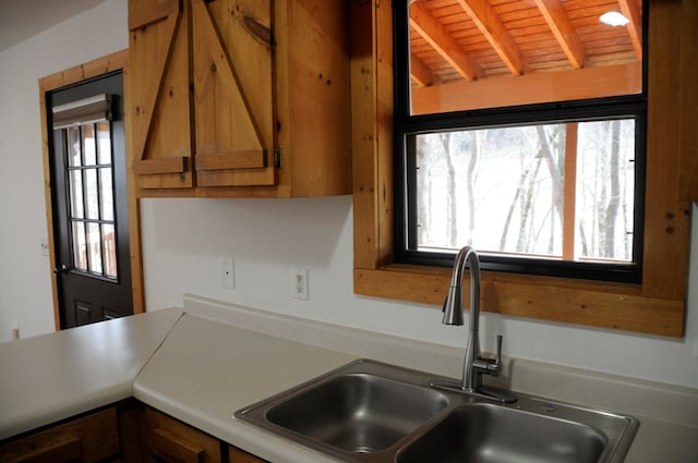 kitchen featuring plenty of natural light, beamed ceiling, wooden ceiling, and sink