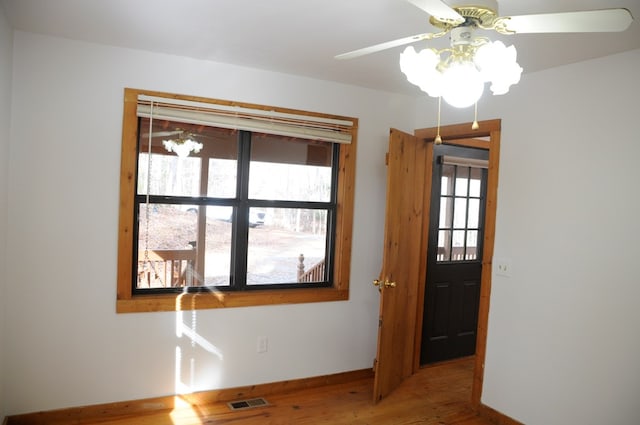 empty room with hardwood / wood-style flooring, plenty of natural light, and ceiling fan