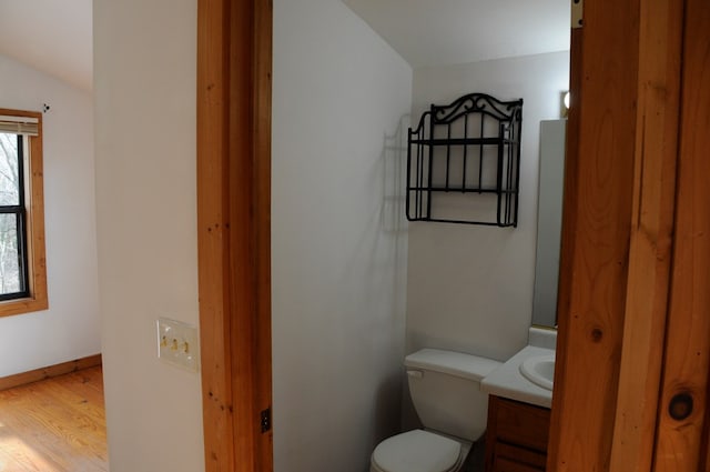 bathroom featuring hardwood / wood-style floors, vanity, toilet, and lofted ceiling