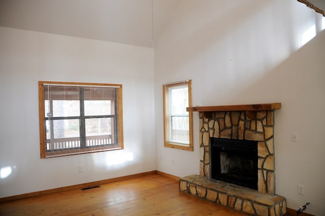 living room featuring a stone fireplace, a wealth of natural light, and light wood-type flooring