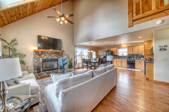 living room with ceiling fan, a fireplace, high vaulted ceiling, light hardwood / wood-style flooring, and wooden ceiling