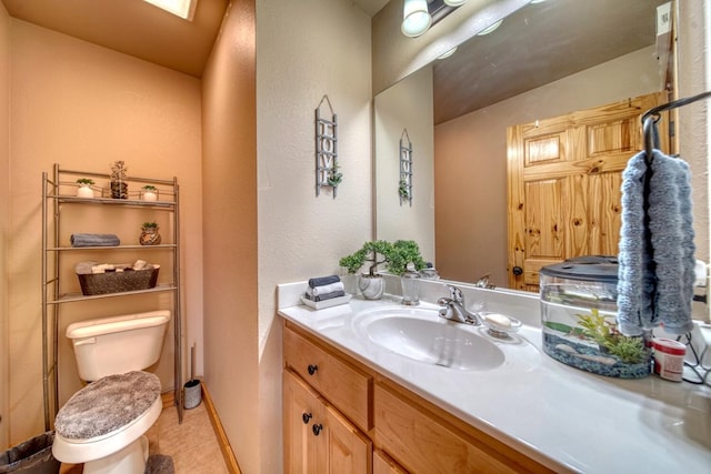 bathroom with toilet, tile floors, and vanity