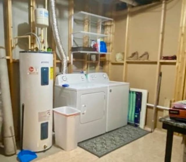 washroom with tile floors, washer and dryer, and electric water heater