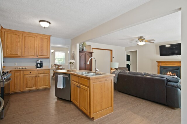 kitchen featuring light hardwood / wood-style flooring, an island with sink, sink, appliances with stainless steel finishes, and a textured ceiling