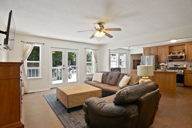 living room with french doors, light hardwood / wood-style flooring, a wealth of natural light, and ceiling fan