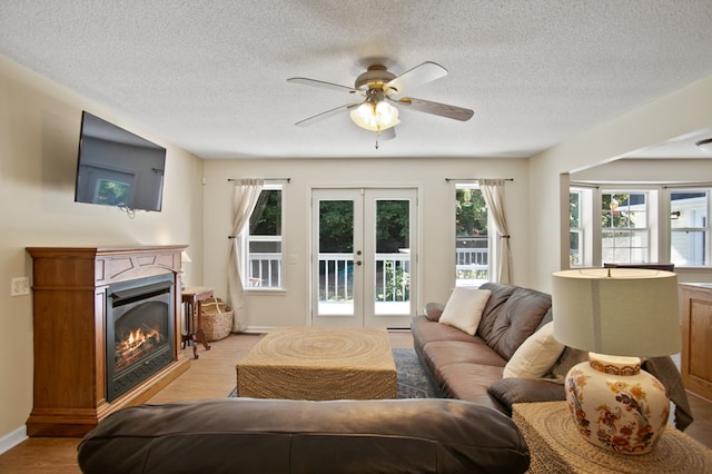 living room with french doors, a textured ceiling, light wood-type flooring, and ceiling fan