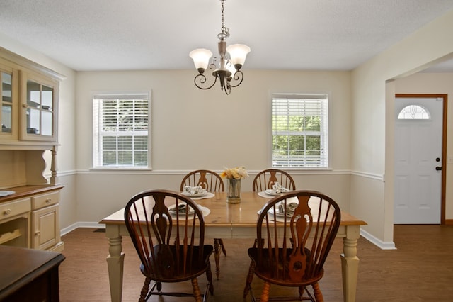 dining room featuring a notable chandelier, dark hardwood / wood-style floors, a textured ceiling, and a wealth of natural light