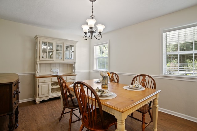 dining area featuring dark wood-type flooring and an inviting chandelier