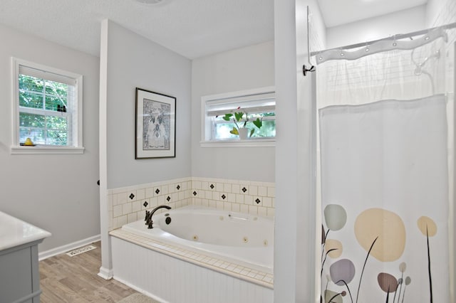 bathroom featuring vanity, hardwood / wood-style floors, plus walk in shower, and a textured ceiling