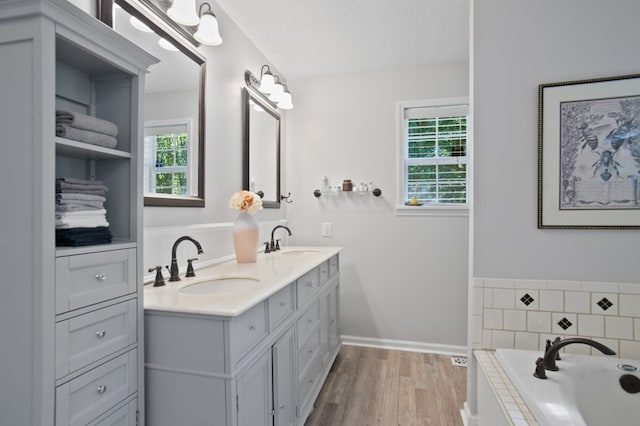 bathroom with vanity, hardwood / wood-style floors, a bathtub, and a textured ceiling