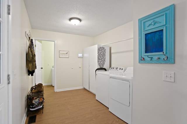 clothes washing area featuring light hardwood / wood-style floors, a textured ceiling, and washing machine and dryer