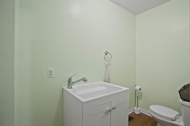 bathroom with toilet, a textured ceiling, vanity, and wood-type flooring