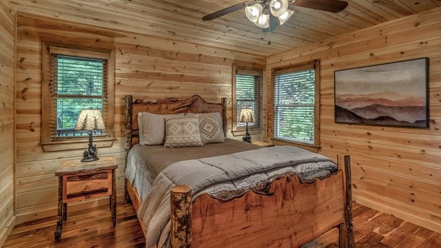 bedroom featuring ceiling fan, hardwood / wood-style floors, and multiple windows