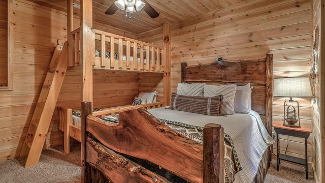 bedroom featuring ceiling fan, wood walls, carpet, and wooden ceiling