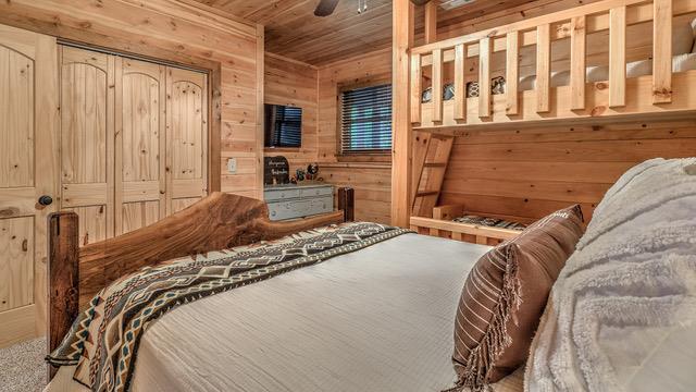 bedroom featuring wooden walls, a closet, and wooden ceiling