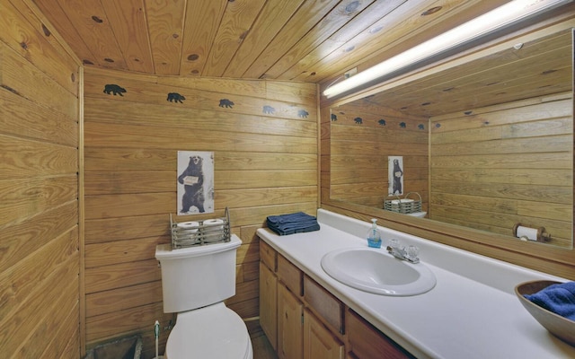 bathroom with vanity, toilet, wood walls, and wooden ceiling