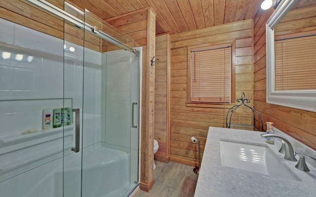 bathroom with wood walls, walk in shower, toilet, and vanity