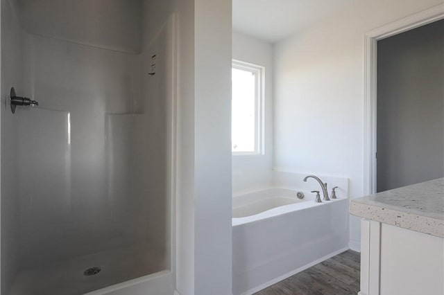 full bathroom featuring a garden tub, a shower, and wood finished floors