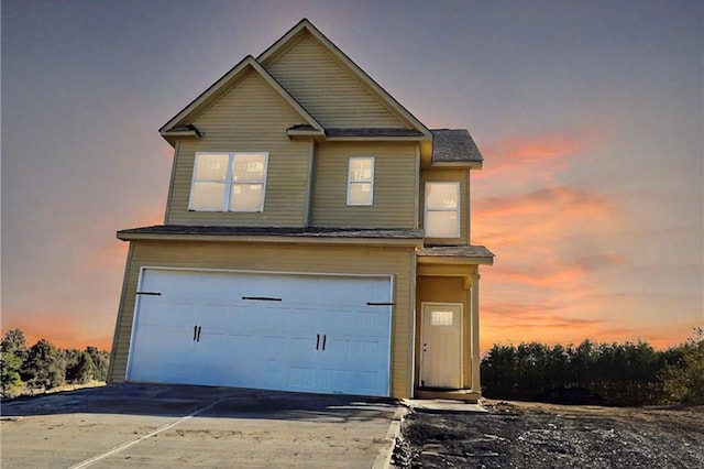 traditional-style home featuring an attached garage, concrete driveway, and roof with shingles