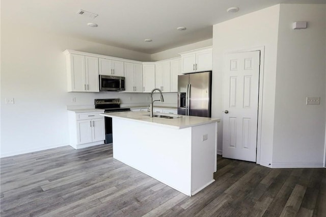 kitchen featuring stainless steel appliances, a sink, dark wood-style flooring, an island with sink, and light countertops