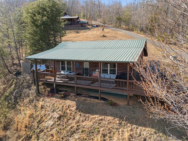 back of house featuring a standing seam roof, log siding, and metal roof