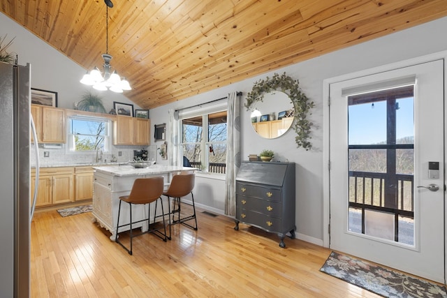 kitchen featuring light wood finished floors, a notable chandelier, light brown cabinetry, and freestanding refrigerator