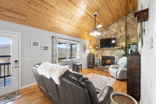 living area with lofted ceiling, wood finished floors, a stone fireplace, baseboards, and wood ceiling