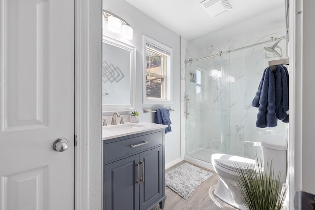 full bath featuring a marble finish shower, visible vents, toilet, wood finished floors, and vanity