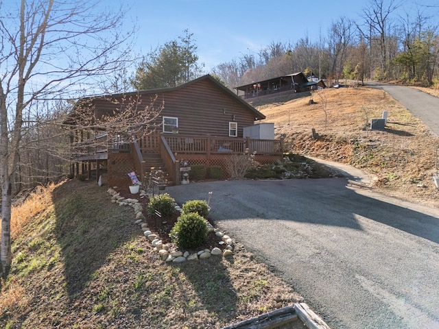 view of side of home with driveway and a deck