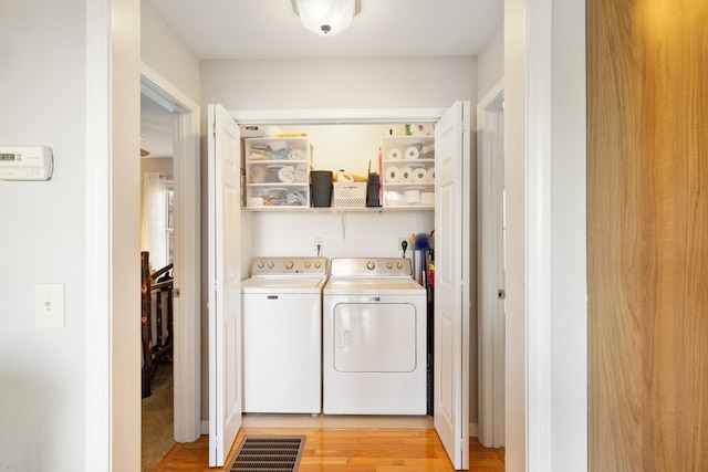 laundry area featuring laundry area, light wood-type flooring, and washer and clothes dryer