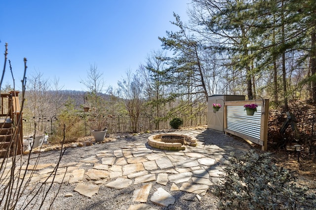 view of patio with a storage unit, fence, an outdoor structure, and an outdoor fire pit