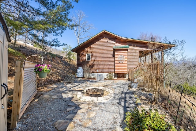 back of property featuring a patio, a fire pit, faux log siding, and fence