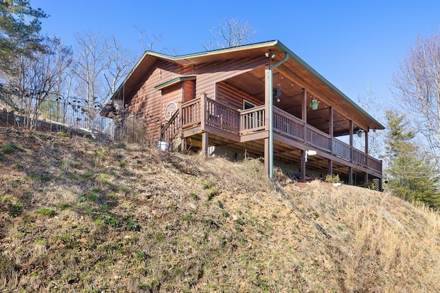 back of house featuring faux log siding and a wooden deck